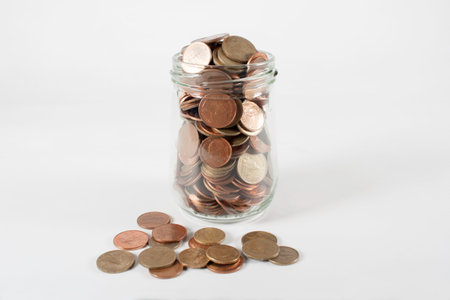 Coins in Glass Jar on the White Background.の写真素材