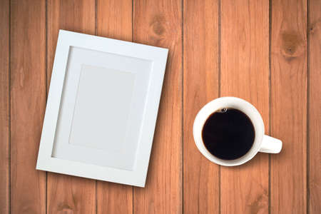 Coffee cup and blank photo frame on wooden table backgroundの写真素材