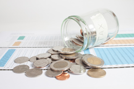 Insurance fund tax with coins in glass jar on budget paper.の写真素材