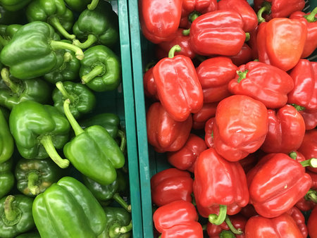 Green and red bell peppers are sold at the outdoor fresh market.