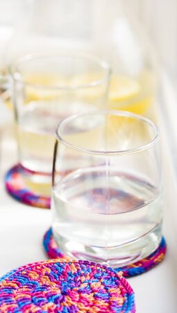 Glass of lemonade on cup coaster with carafe next to itの写真素材