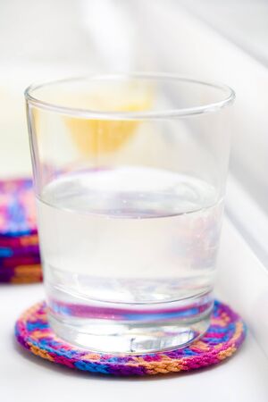 Glass of lemonade on cup coaster with carafe next to itの写真素材