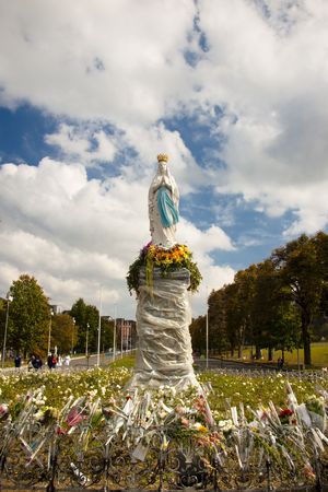 Clouds on the sky and Big figure of the Madonna in Lourdes - France. Autumn day.の写真素材