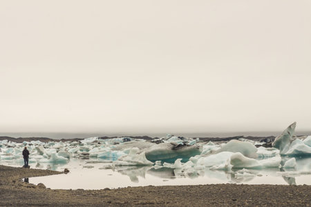 Man on coast of Glacier lake - Jokulsarlon lagoon, Iceland の写真素材
