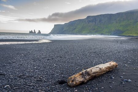 Beauty dark sandy beach in background Dyrholaey stone - Vik, Iceland. Summer sunny day.の写真素材