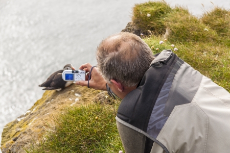 Puffin bird and photographer with digital camera on Latrabjarg, Iceland.の写真素材