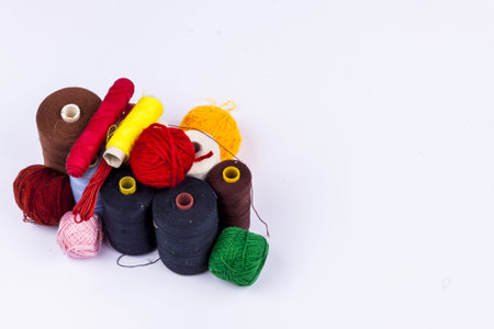 Colourful threads and wool on white background.