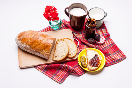 Bread with plum jam cup of milk on white. Studio shot.