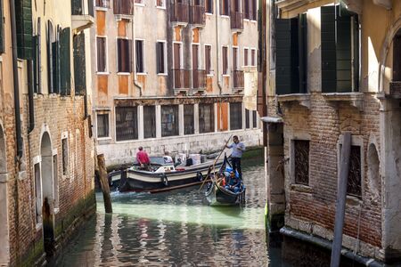 VENICE, ITALY -  MAY 2, 2019: Tourists travel on gondolas at canal on May 2,2019 in Venice in Italy. Gondola trip is the most popular touristic activity in Venice.のeditorial素材