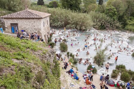 SATURNIA, ITALY - MAY 1, 2019: Tourists swimming and relaxing in hot springs in Saturnia at Mulino natural waterfalls by Manciano municipality in tuscan Maremma on May 1,2019 in Saturnia, Italy.のeditorial素材
