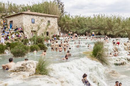 SATURNIA, ITALY - MAY 1, 2019: Tourists swimming and relaxing in hot springs in Saturnia at Mulino natural waterfalls by Manciano municipality in tuscan Maremma on May 1,2019 in Saturnia, Italy.のeditorial素材