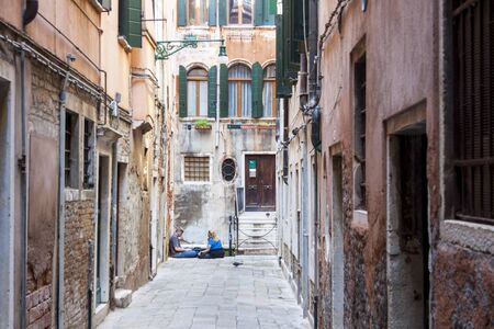 VENICE, ITALY -  MAY 2, 2019: Tourists relaxing in a narrow street on May 2,2019 in Venice in Italy.のeditorial素材