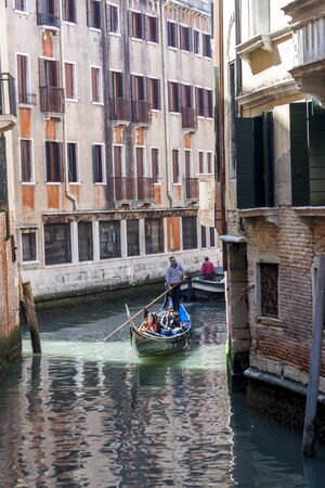 VENICE, ITALY -  MAY 2, 2019: Tourists travel on gondolas at canal on May 2,2019 in Venice in Italy. Gondola trip is the most popular touristic activity in Venice.のeditorial素材