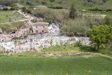 SATURNIA, ITALY - MAY 1, 2019: Tourists swimming and relaxing in hot springs in Saturnia at Mulino natural waterfalls by Manciano municipality in tuscan Maremma on May 1,2019 in Saturnia, Italy.のeditorial素材