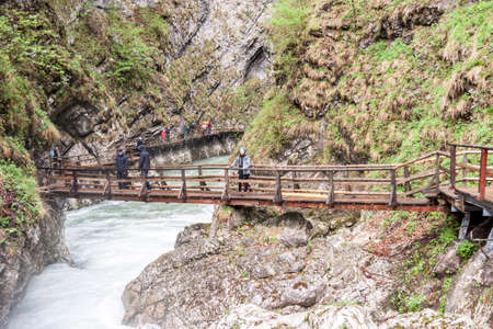 Bled, Slovenia - April 24, 2019: People walking on wooden bridges at Vintagr gorge as the Radovna River flows fast with lush green surrounding nature.のeditorial素材