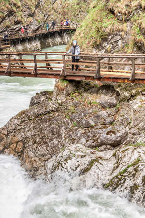 Bled, Slovenia - April 24, 2019: People walking on wooden bridges at Vintagr gorge as the Radovna River flows fast with lush green surrounding nature.のeditorial素材