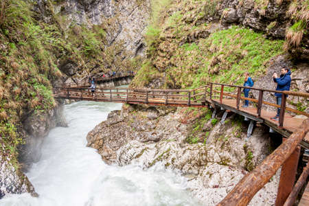 Bled, Slovenia - April 24, 2019: People walking on wooden bridges at Vintagr gorge as the Radovna River flows fast with lush green surrounding nature.のeditorial素材