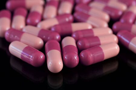 Two-coloured medicine pills, big closeup  and reflection on black backgroundの写真素材