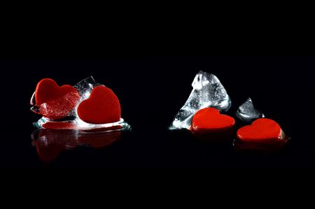 Four hearts in almost melted ice cubes with  reflection on black backgroundの写真素材