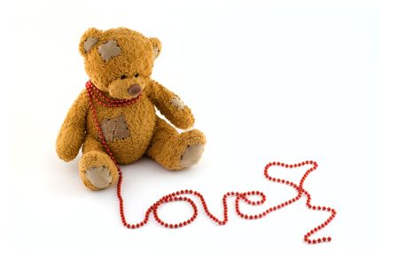 Sweet teddy bear with a string of red beads arranged to love at isolated white backgroundの写真素材