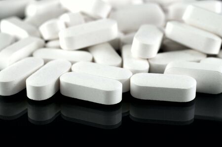 White medicine pills in big closeup with reflection at black backgroundの写真素材
