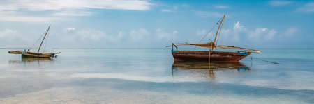 Zanzibar in Tanzania, typical fishing boat on a beautiful beach with wavesの写真素材