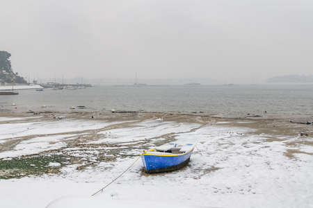 Brittany, the Ile aux Moines, with a sailing boat in the harbor in winter, under the snowの写真素材
