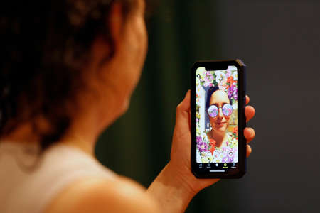 Quebec, Canada - 08/31-2021: A woman is having fun with the face app with Snapchat on her cell phoneのeditorial素材