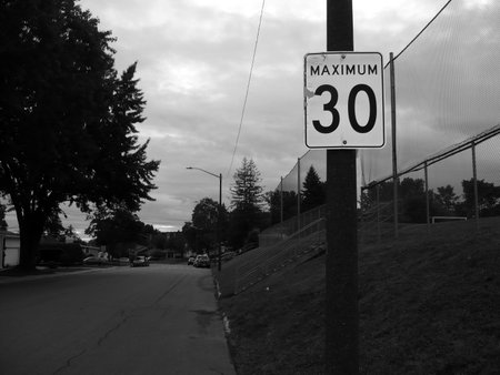 A black and white shot of a speed limit sign on a streetの写真素材