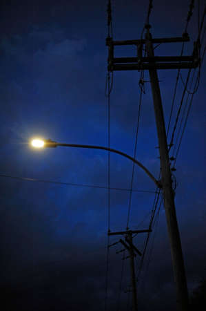 an electric pole in town at nightの写真素材