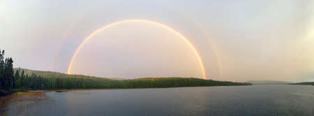 a rainbow over the lake in the forestの写真素材