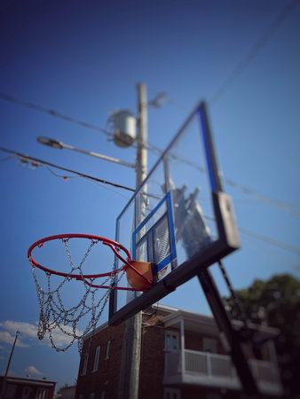 Basketball hoop and net against blue sky in a residential area.