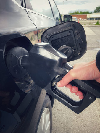 Hand refilling car with fuel at gas station. Close up.