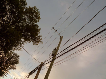 Silhouette of electric pole and wire with blue sky background.