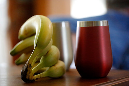 Banana juice in a red glass and fresh bananas on the tableの写真素材