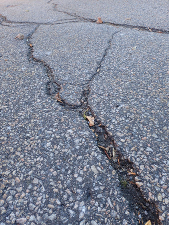 Cracks on the asphalt road, close-up of photo.の写真素材