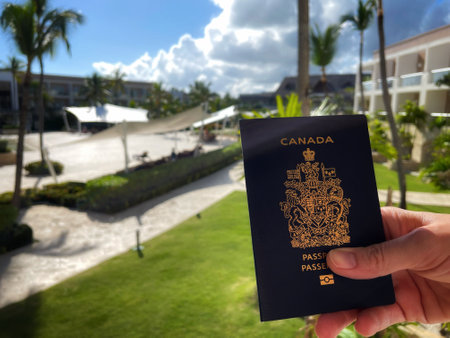 hand holding a Canadian passport against a background of palm trees and tropical plantsのeditorial素材