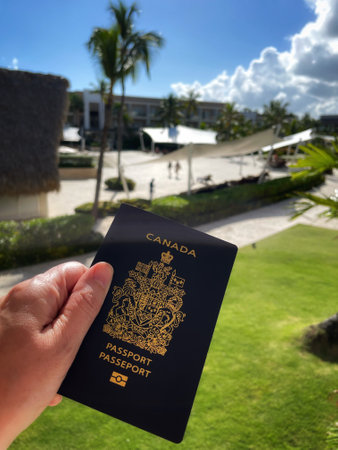 hand holding a Canadian passport against a background of palm trees and tropical plantsのeditorial素材