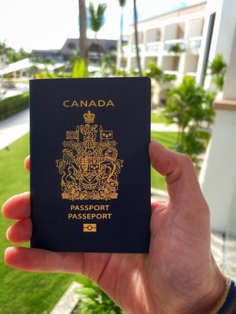 hand holding a Canadian passport against a background of palm trees and tropical plantsのeditorial素材