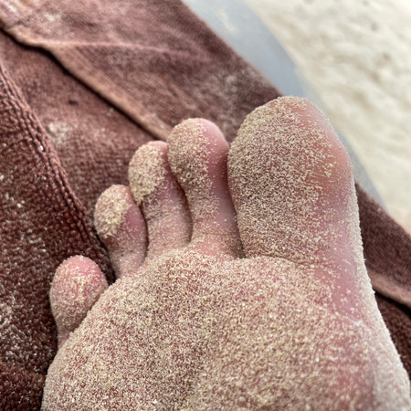 Feet of a man lying on a towel in the sand.の写真素材