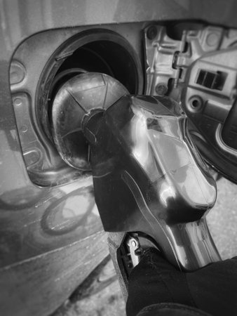 Close-up of a man putting gasoline into a car at a gas station