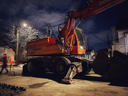 A mechanical excavator on a road construction site at nightのeditorial素材