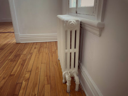 Antique floor-mounted hot water radiator in a room in an apartment.