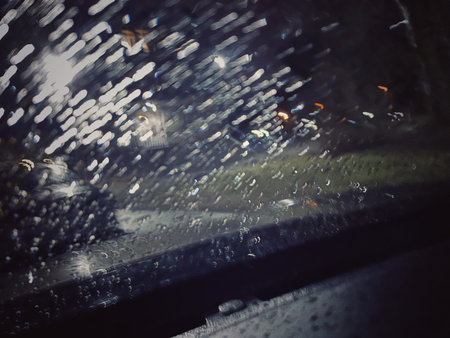 Raindrops on the car windshield. Shallow depth of field. Driving a car fast on a rainy evening.