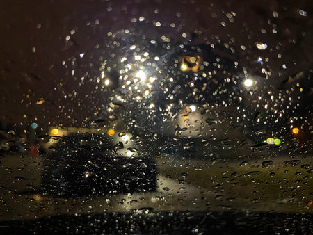 Drops of rain on the car windshield at night. Driving a car fast on a rainy evening.