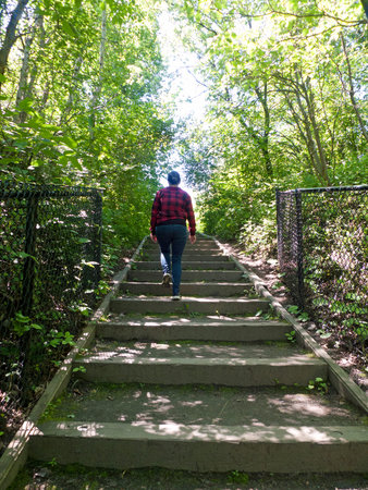 A woman walks up the stairs in the forest. View from the back.