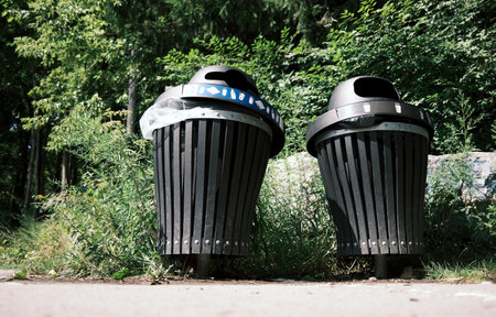 Two black garbage bins in the park on a sunny summer day.の写真素材