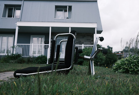 An abandoned office chair on the grass in front of a house