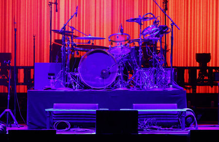 Drum set on stage with red curtains in the background. Blue light.の写真素材