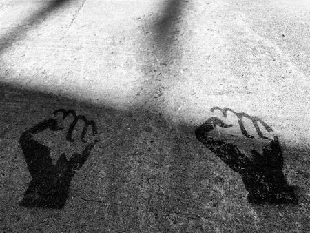 Black and white image of a pair of closed human hands printed on the sidewalk.の写真素材